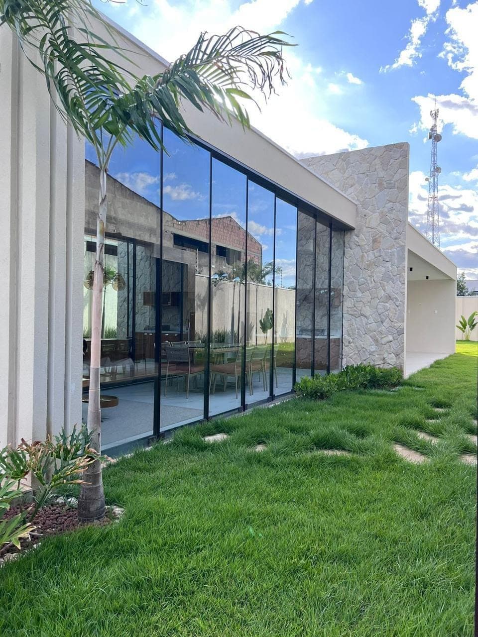 Fachada de vidro com jardim e céu azul